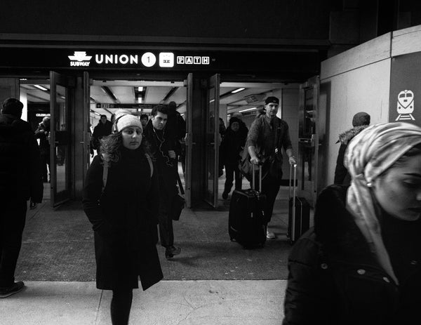Traveler with luggage navigating Toronto's busy subway station at night