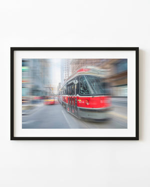 Red Toronto TTC streetcar surrounded by motion-blurred city traffic