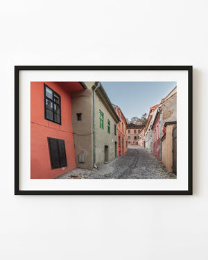 Empty cobbled street lined with colourful historic houses in Transylvania.