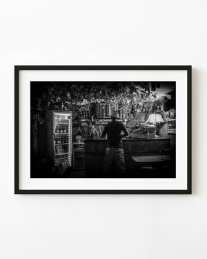 Man in a cowboy hat at a richly decorated Trinidad bar in black and white.