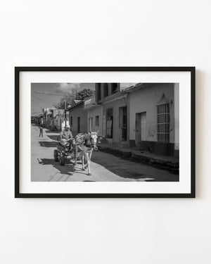 Horse-drawn carriage and driver on a sunlit street in Trinidad Cuba, in black and white.