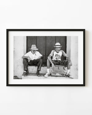 Two men in straw hats smoking cigars on a doorstep in Trinidad Cuba.