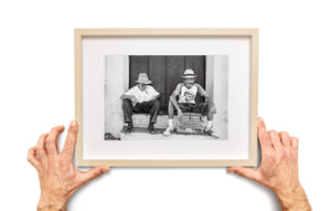 Men wearing straw hats sit on stone steps in Trinidad Cuba.