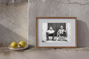 Black and white Cuban doorstep scene with cigar-smoking men in straw hats.