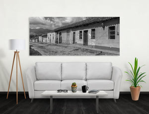 Monochrome Cuban architecture beneath clouds and distant mountain ridges.