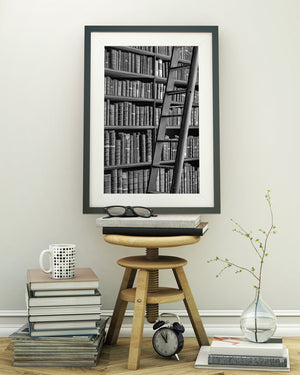 Black and white photograph of worn book spines and a leaning library ladder.