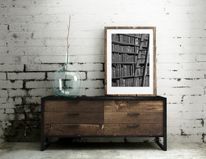 Rows of antique books form a textured backdrop to a wooden ladder.