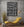 Vertical library photograph with aged volumes and dark wooden shelving.