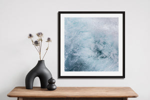Abstract nature photograph of churning sea foam in pale blue and white.
