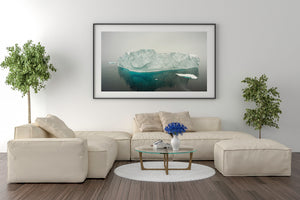 Pale blue Antarctic ice reflected in calm dark water amid falling snow.