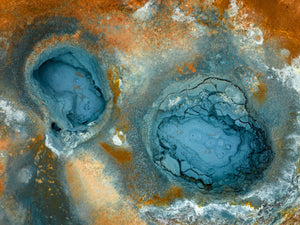 Two blue geothermal pools amid rust-orange and pale mineral textures.