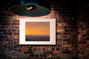 Softly layered Tuscan ridges beneath a broad glowing evening sky.