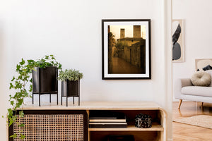 A stone arch spans a quiet laneway below Tuscan towers.
