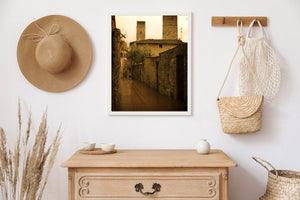 Golden-brown tones highlight textured stone buildings along a narrow Tuscan lane.