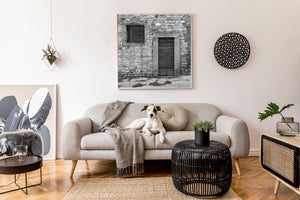 A narrow stone-framed door beside an iron-grilled window in Tuscany.