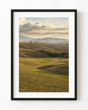 Tuscan farmhouse and cypress-lined fields beneath softly lit clouds.