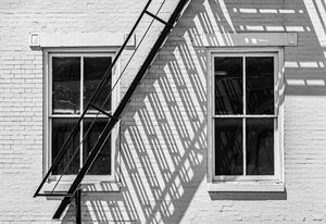 Urban fire escape detail with twin windows and aging facade