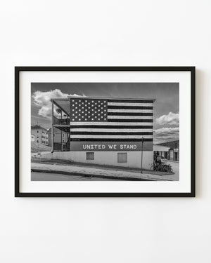 American flag mural with United We Stand lettering on a brick building in black and white.