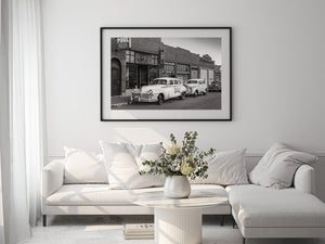 Monochrome streetscape featuring vintage vehicles and historic storefronts