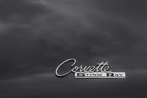 classic Corvette Sting Ray script emblem on dark car surface monochrome
