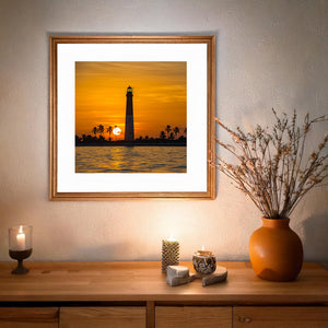Coastal lighthouse scene at sunset with palm trees