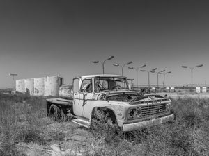 Old industrial fuel truck rusting in field near Sidney Nebraska monochrome
