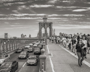 Cars and people crossing the Brooklyn Bridge in black and white