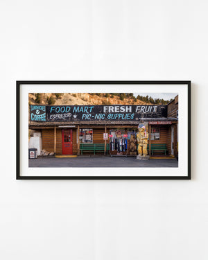 Utah log storefront with a red door, painted food mart signs and wooden figures