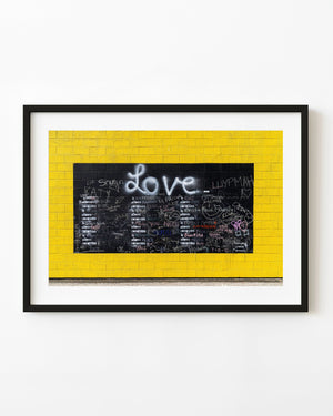 Love chalkboard filled with colorful writing on a bright yellow wall in Vancouver