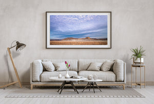 Desert mesas and pale eroded slopes below a sweeping cloud-filled sky