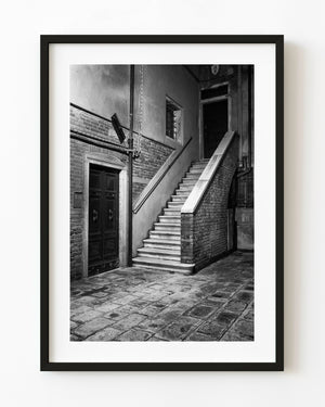 Stone stairs and dark wooden doors in a Venice courtyard in black and white
