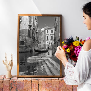 Passagiere sitzen in einer Gondel unter hohen Fassaden mit Fensterläden in Venedig