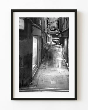Blurred walkers in a narrow Venice laneway photographed in black and white