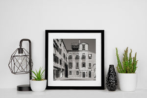 Venetian homes with flower-filled window boxes and a person on a rooftop terrace