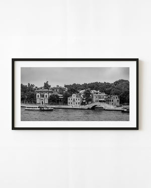 Venice waterfront homes and an arched footbridge with a passing waterbus in black and white