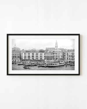 Venice waterfront with moored passenger boats and historic facades in black and white