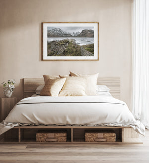 A frozen Norwegian lake stretches beyond green moss and rough shoreline stone