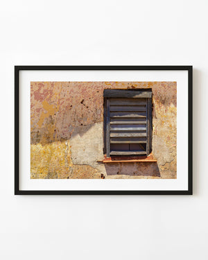 Weathered wooden shutter in a peeling yellow wall in Vinales, Cuba