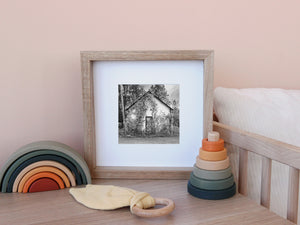 Black and white view of a weathered country building overtaken by vines