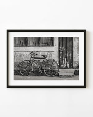 Vintage bicycle leaning against a weathered wall and wooden door in India in black and white