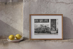 Black and white photograph of an aged bicycle beside a chipped concrete step