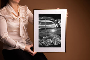Light glints across a vintage automobile body beneath a chrome antenna