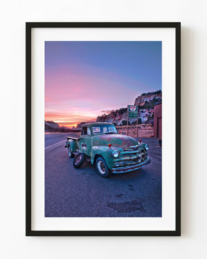 Weathered turquoise Chevrolet pickup beside a Utah road under a pink sunset sky