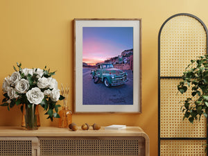 Pink sunset light above Utah cliffs and an aged turquoise Chevrolet pickup