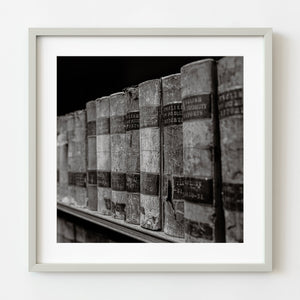 Framed black and white photograph of vintage books on a shelf.