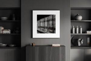 Framed artwork on a wall in a modern interior setting with shelves and decor.