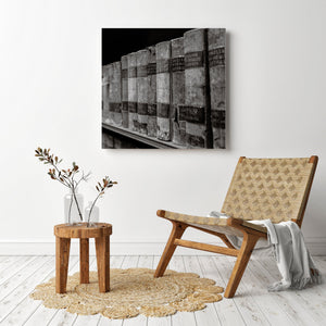 Wooden chair with woven backrest in a room with a wall art piece of old books.