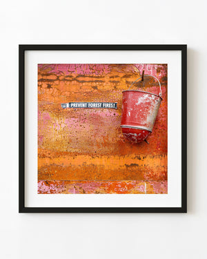 Vintage red fire bucket against peeling orange and pink paint.