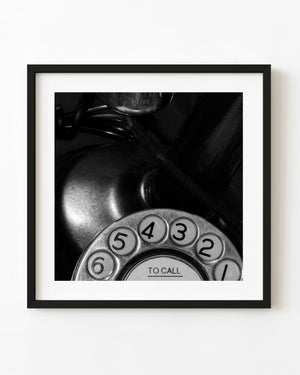 Black and white detail of a vintage rotary telephone dial and cord.