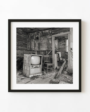 Vintage television and wooden chair in an abandoned Saskatchewan farmhouse.